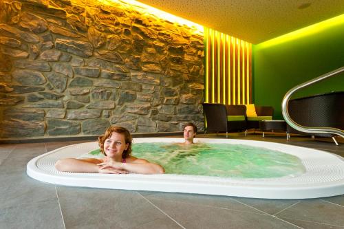 dos personas en una bañera de hidromasaje en un hotel en Hotel Teichwirt en Fladnitz an der Teichalm