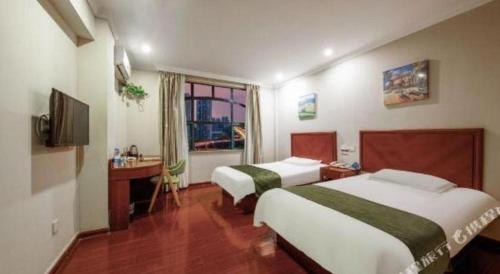 una camera d'albergo con due letti e una televisione di GreenTree Inn Shanghai MinHang ZhuanQiao Subway Station East ZhuanXing Road Shell Hotel a Shanghai