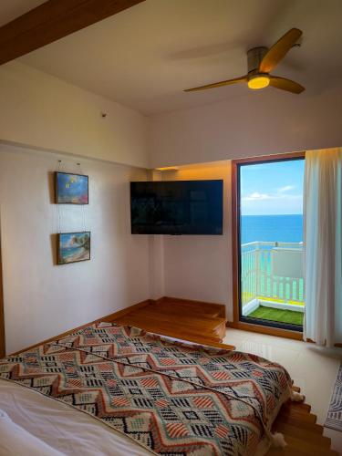 a bedroom with a bed and a large window at Aqua Horizon Beachside Condo I Signature Art Suites in Dauis