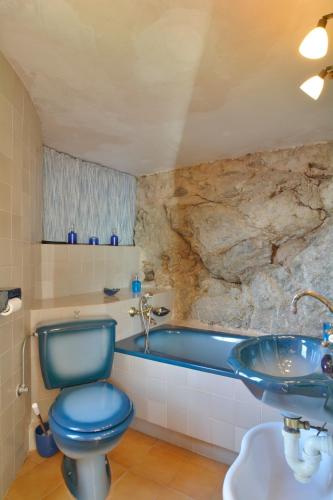 a bathroom with a blue toilet and a bath tub at Sa Cova Banyalbufar in Banyalbufar