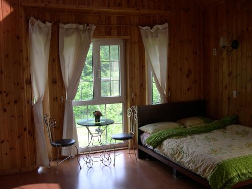 a bedroom with a bed and a window and a table at Happy Dream Pension in Pyeongchang