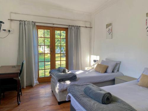 Somerset EastにあるLittle Rock Mountain Houseのベッド2台と机と窓のある寝室