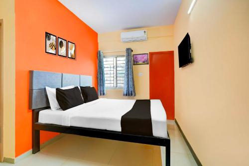 a bed in a room with an orange wall at Hotel O Electronic City in Kammasandra