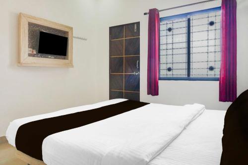 a bedroom with a bed and a window with pink curtains at Hotel O Mahabaleshwar Near Mapro Garden in Mahabaleshwar