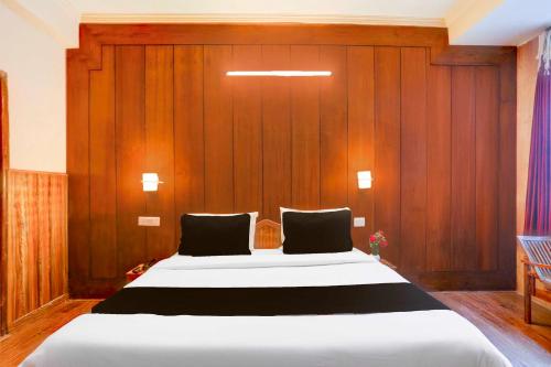 Un dormitorio con una cama grande con una pared de madera. en Hotel O Manali Near Hadimba Temple, en Manali