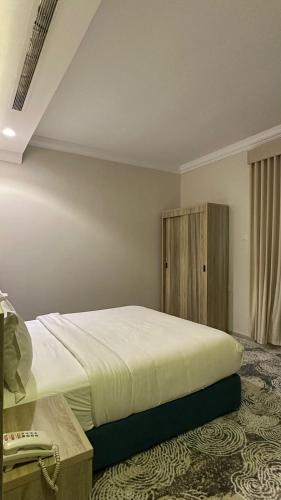a bedroom with a large bed and a wooden cabinet at راحتي للشقق المخدومة in Taif