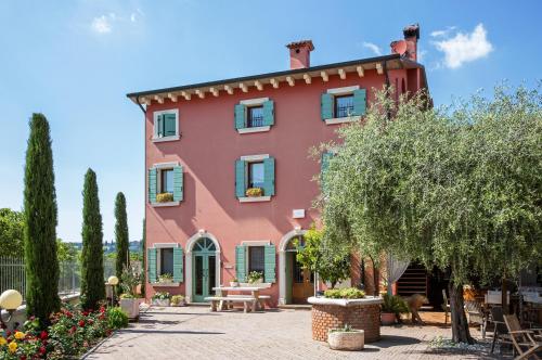 ein großes rotes Haus mit einer Terrasse und Bäumen in der Unterkunft Relais Ca' Maddalena in Villafranca di Verona