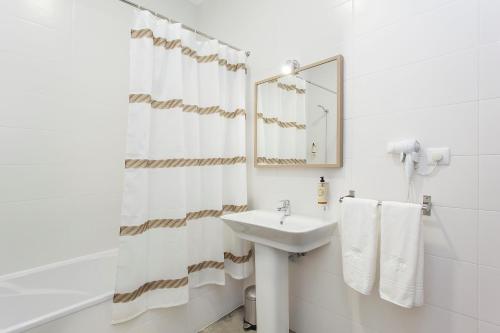 a white bathroom with a sink and a mirror at Emporium Lisbon Suites in Lisbon