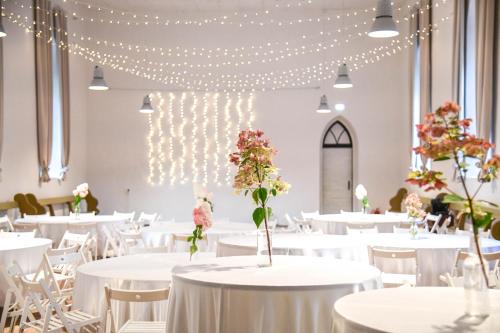 a banquet hall with white tables and chairs and lights at UKI Puhkeküla in Ranna