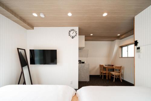a bedroom with two beds and a tv on a wall at Sunshine Inn 456 - Economic APT in Tokyo Tranquil Block, with Direct Access to Ginza & Akihabara in Tokyo