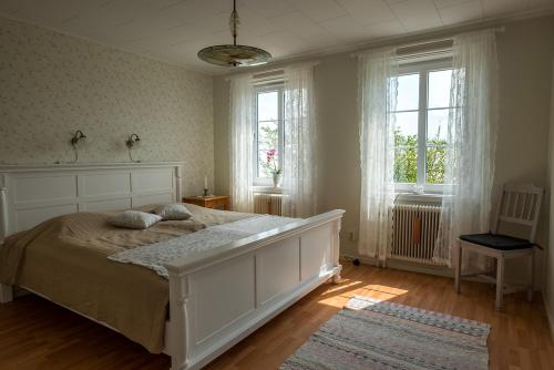 a bedroom with a large white bed and two windows at Råshults Gård in Vimmerby