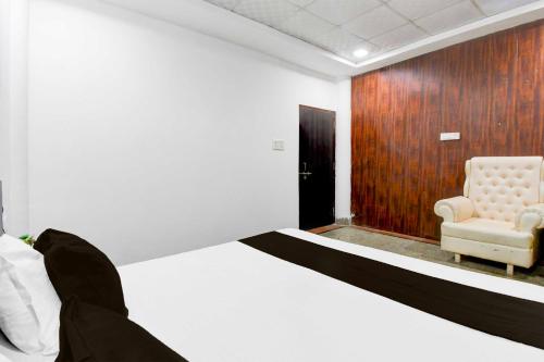 a bedroom with a white bed and a chair at Hotel O Vrindavan Yojna Lucknow in Lucknow