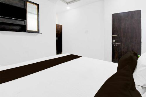 a bedroom with a white bed and a wooden door at Hotel O Vrindavan Yojna Lucknow in Lucknow