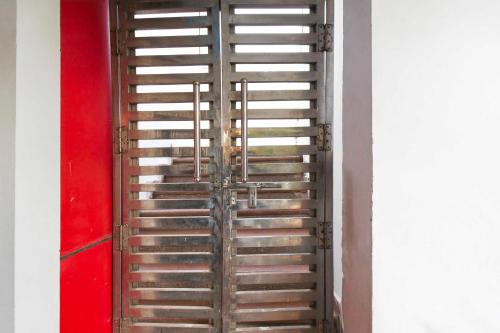 a metal door in a room with a red wall at Hotel O Vrindavan Yojna Lucknow in Lucknow