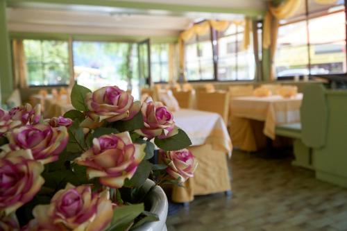 a room with tables and a vase with pink flowers at Hotel Seeblick in Döbriach