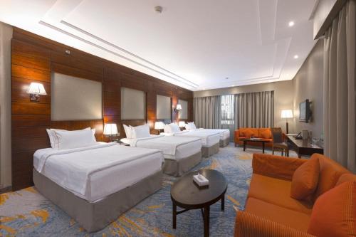 a hotel room with four beds and a couch at Ruve Al Madinah Hotel in Medina