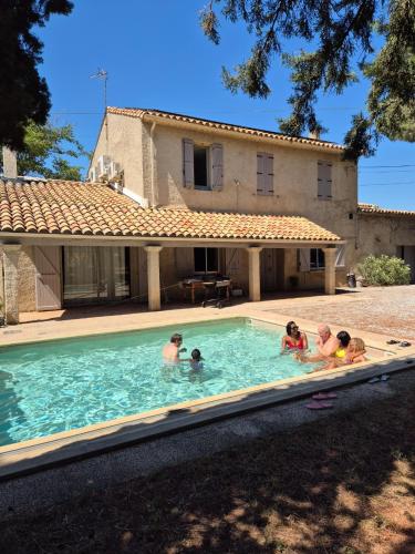 - un groupe de personnes dans une piscine en face d'une maison dans l'établissement Mas de la vigne, à Montredon