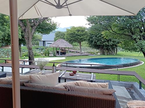 eine Terrasse mit Sonnenschirm und Swimmingpool in der Unterkunft Chompor MaeWang ฌอมภอ in Ban Nong Yen