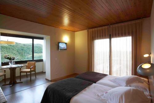 a bedroom with a bed and a table and a window at Hotel Calitxo in Molló