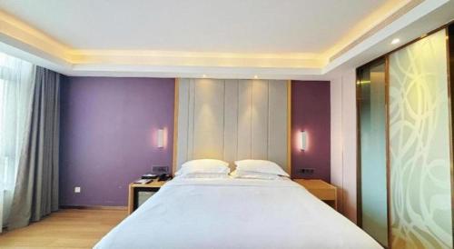 a large bed in a room with purple walls at Lavande Hotel·Dongxing Port in Fangcheng