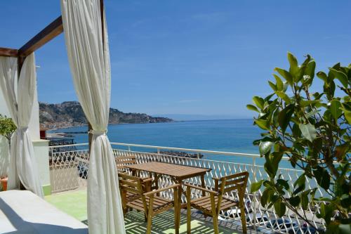 
a dining room table with a balcony overlooking the ocean at Mediterraneo Guesthouse in Giardini Naxos
