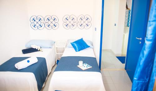 two beds in a room with blue and white at Blue Suite in Castellammare del Golfo