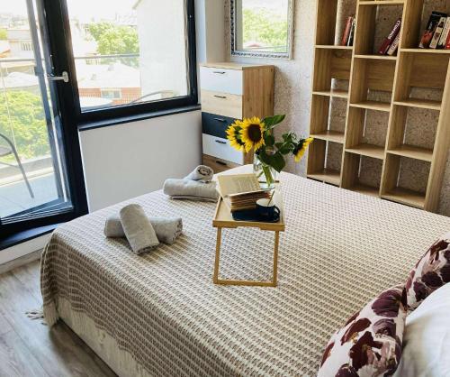 a bedroom with a bed with a table with a sunflower on it at Panoramic apartment in Varna with underground parking in Varna City