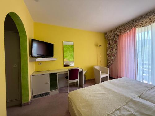 a hotel room with a bed and a desk with a tv at Hotel Seeblick in Döbriach