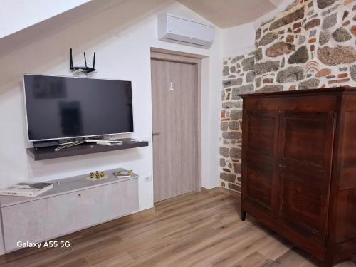 a living room with a tv and a stone wall at Biginau ' e giosso in Ilbono