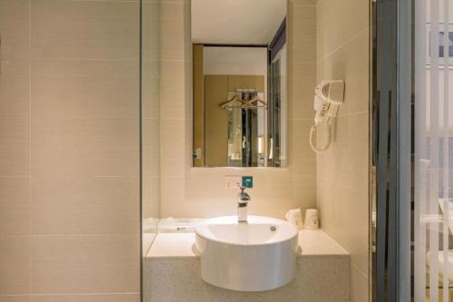 a bathroom with a white sink and a mirror at City Comfort Inn Dangtu High Speed East Railway Station RT-Mart in Ma'anshan