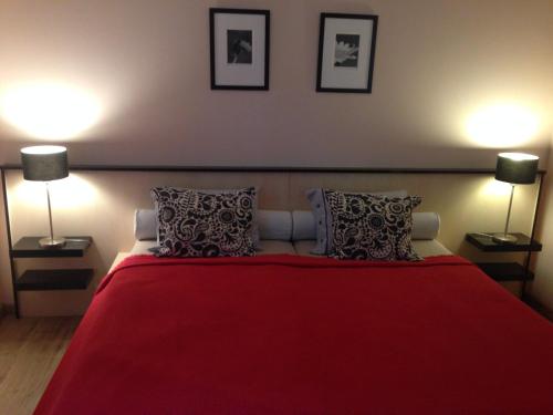 a bedroom with a red bed with two lamps at Albatrosz Apartman in Gyula