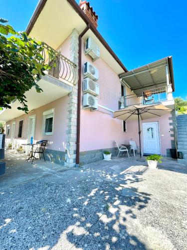 a building with a patio with chairs and an umbrella at 4 Roses Residence in Sečovlje