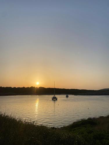 a boat in the water with the sunset in the background at Els Vents OM IN WHITE, Refugio Zen en Son Parc, tranquilidad a 5 minutos de la playa in Son Parc