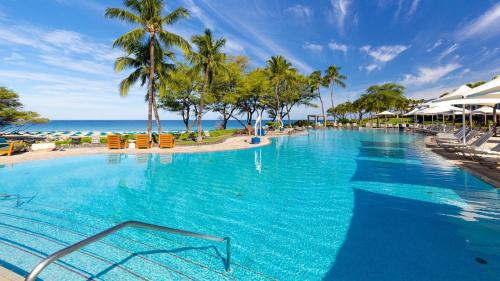 a large swimming pool with palm trees and the ocean at ❤PiH❤MAUNA KEA DREAM We ︎ Families Private Heated PoolSpa Stunning Views in Hapuna Beach