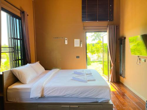 un letto con asciugamani sopra in una stanza con una finestra di Bergen Resort Khon Kaen a Khon Kaen