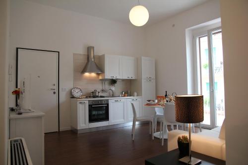 a kitchen with white cabinets and a table with chairs at DomusApuliae Apartments in Monopoli