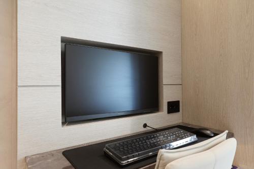 a computer monitor and a keyboard and mouse on a desk at Hound Hotel Asan Terminal in Asan