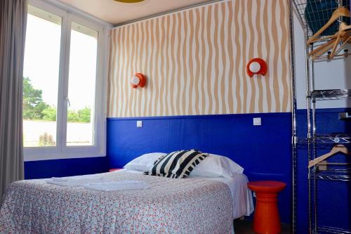 a bedroom with a bed with blue walls and a window at Hôtel Océan in Capbreton