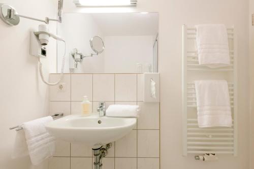 a white bathroom with a sink and towels at Hotel auf den Hummerklippen in Helgoland