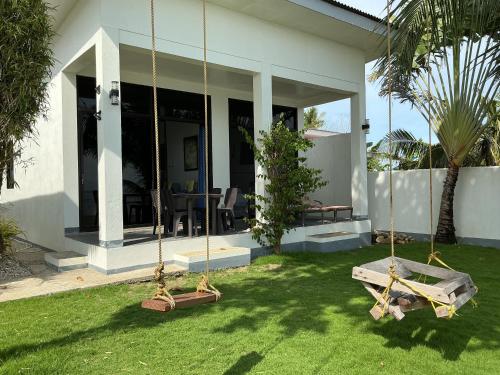 a house with two swings in the yard at BambooBeachVilla1 AC New OCEANFRONT POOL sunsetview garden kitchen SATELLITE STARLINK WI-FI in Dimiao