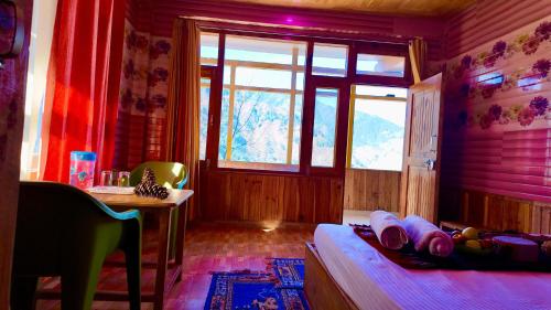 a bedroom with a bed and a window and a table at MountView - A Homestay in Jibhi