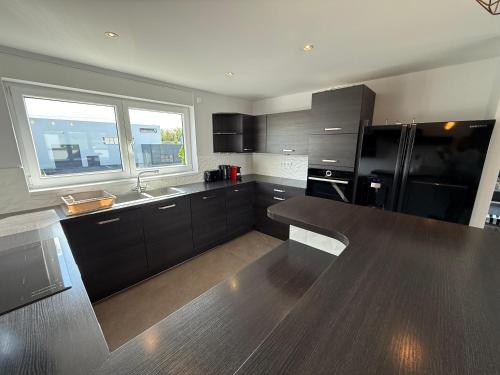 - une cuisine avec des armoires noires et un réfrigérateur noir dans l'établissement Appartement attique, à Dietwiller