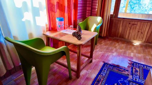 a small table and two green chairs in a room at MountView - A Homestay in Jibhi