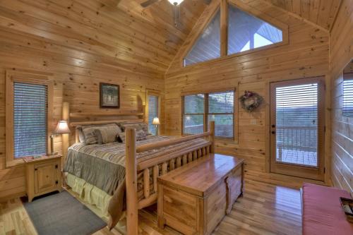a log cabin bedroom with a bed and windows at Sweet Seclusion Firepit king suite serene outdoor spaces in Mineral Bluff