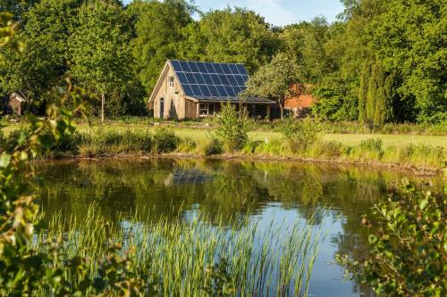 a house with solar panels on its roof next to a lake at het Atelier in Eext