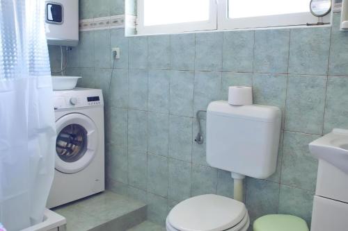 a bathroom with a toilet and a washing machine at Small Nature house Teodora in Novalja