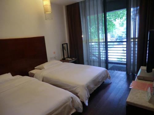 a hotel room with two beds and a balcony at Guangzhou Fangyuan Hotel - Free Shuttle Bus to Canton Fair Complex during 14th Oct to 3rd Nov in Guangzhou