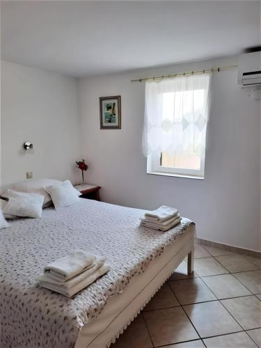 a white bedroom with a bed with towels on it at Small Nature house Teodora in Novalja