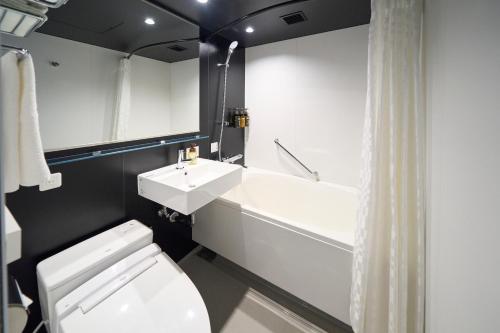 a bathroom with a toilet and a sink and a tub at Hotel Resol Ueno in Tokyo