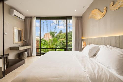 a bedroom with a large white bed and a large window at Baliris Canggu Villa by Betterplace in Tumbak Bayuh